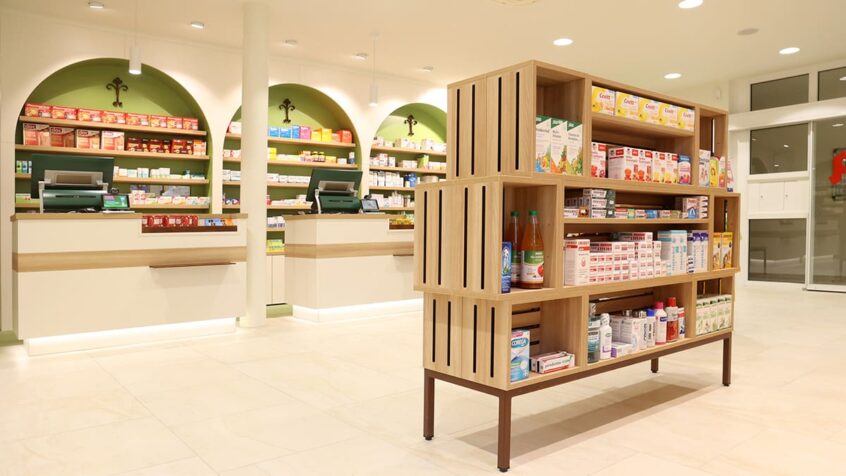 Elisabeth-Apotheke Freyburg Regal mit vier Standfüßen in moderner Holzoptik & Kassenbereich mit zwei Kassen im Hintergrund